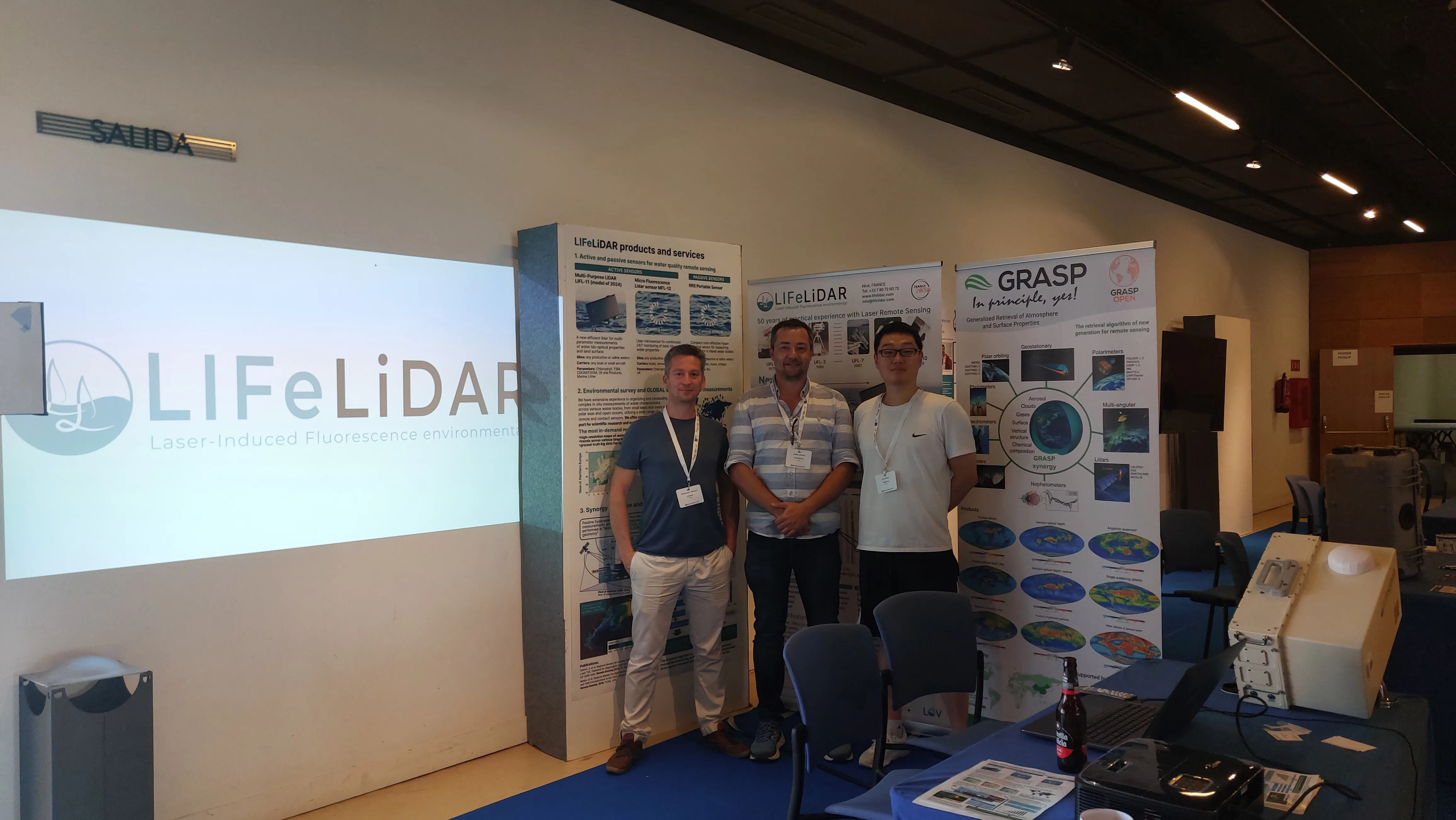 Three attendees beside the LIFeLiDAR exhibition display at an earlier event