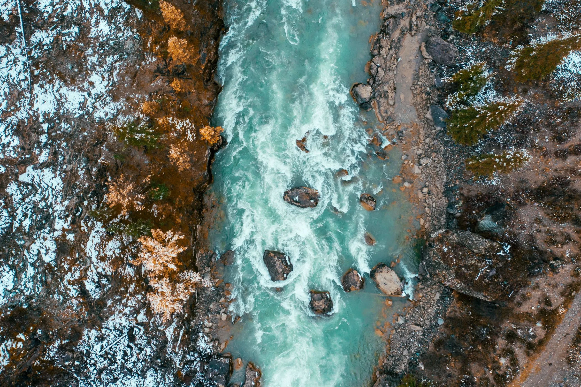 A glacial-fed river seen from directly above, turquoise water running between rocky banks